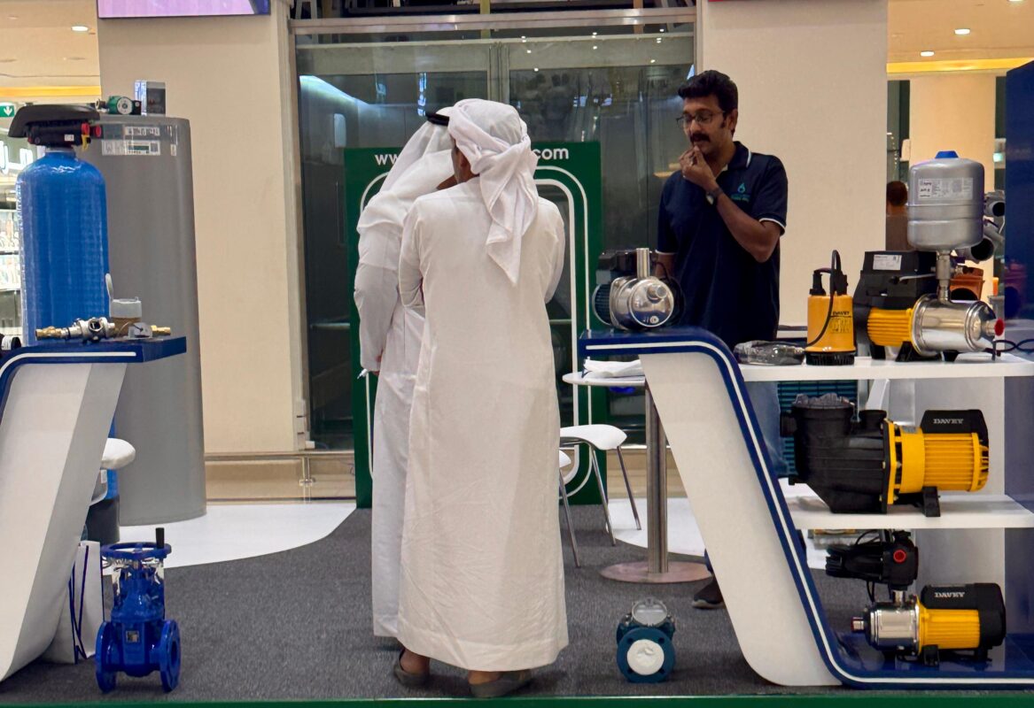 Moosa-Daly team member discussing pump system features with Emirati visitors at Madinat Zayed event.